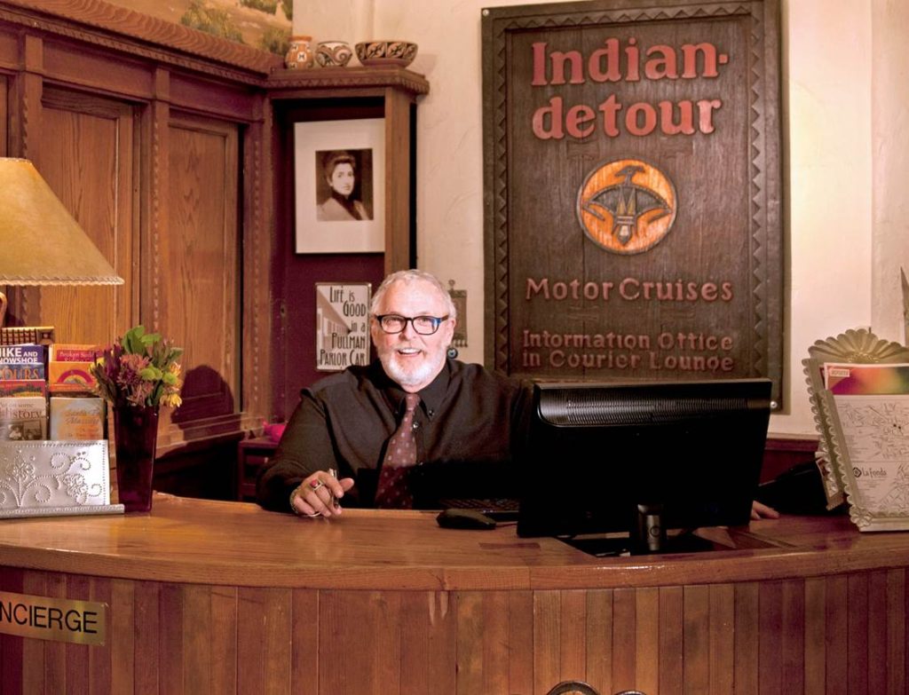 Image of white man sitting at hotel concierge desk